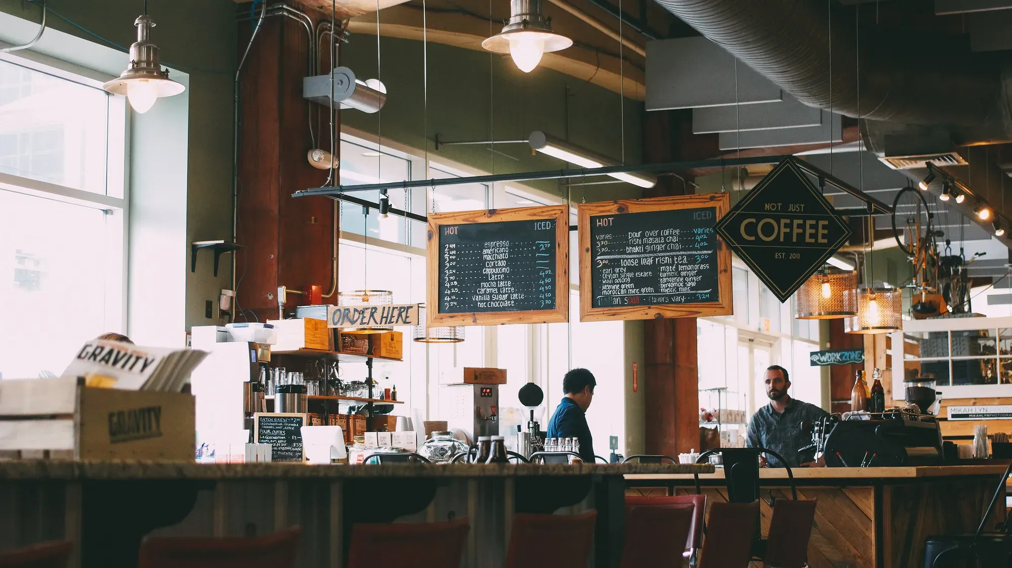 Two people talking across the counter of a small coffee shop